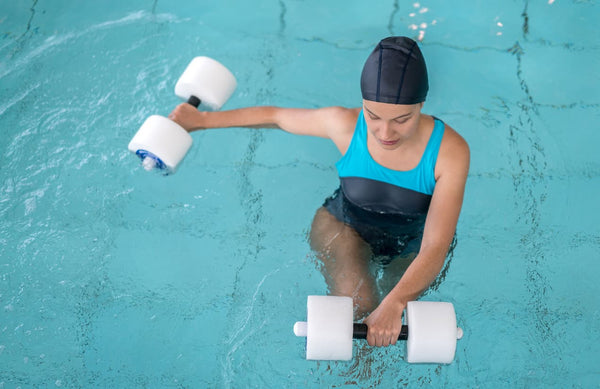 A woman does aquatic therapy with foam weights in a swim spa