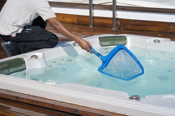 A man performing hot tub maintenance with a skimmer  